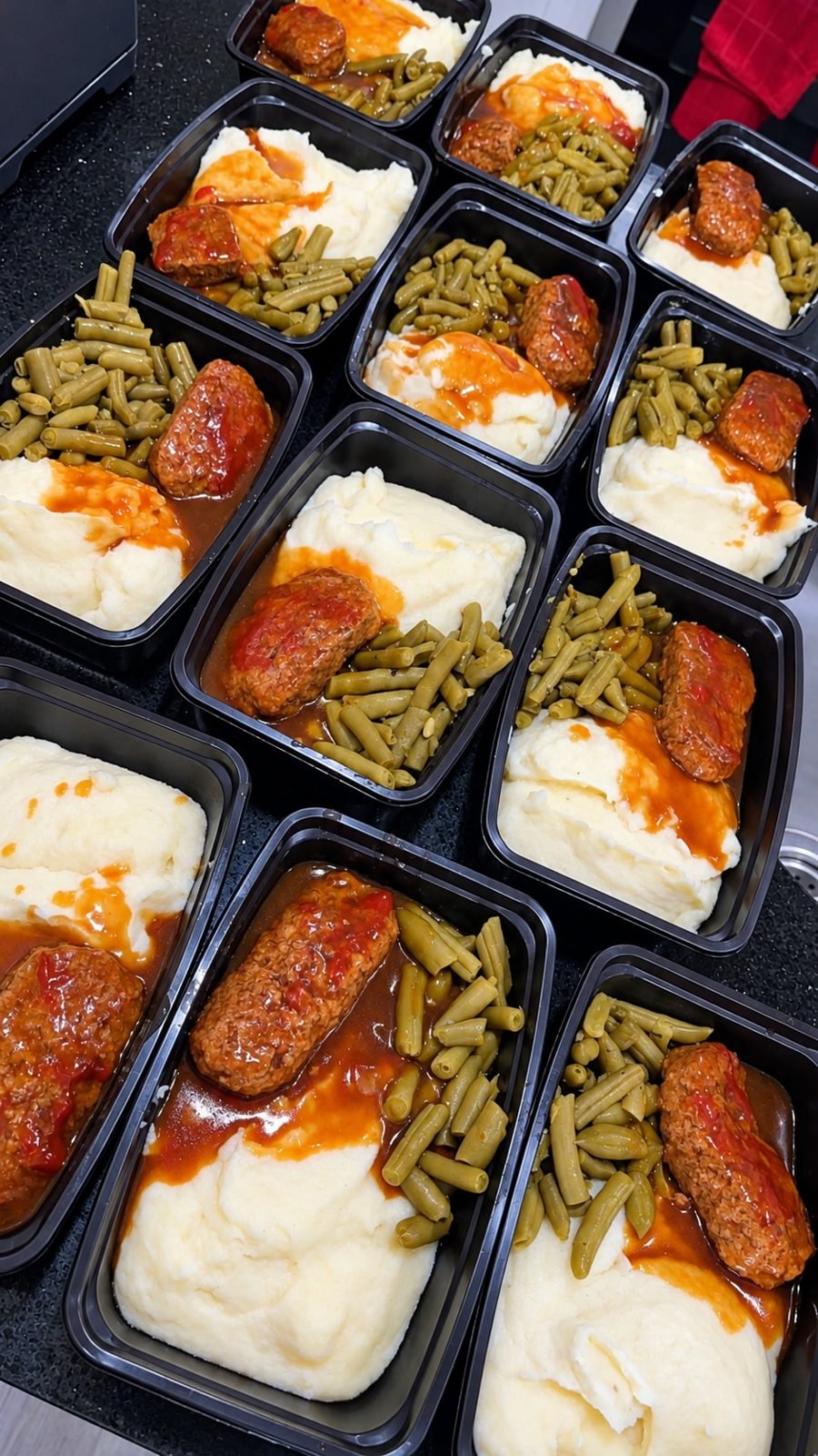 Rows of packed hot meals: meatloaf, mashed potatoes, and green beans
